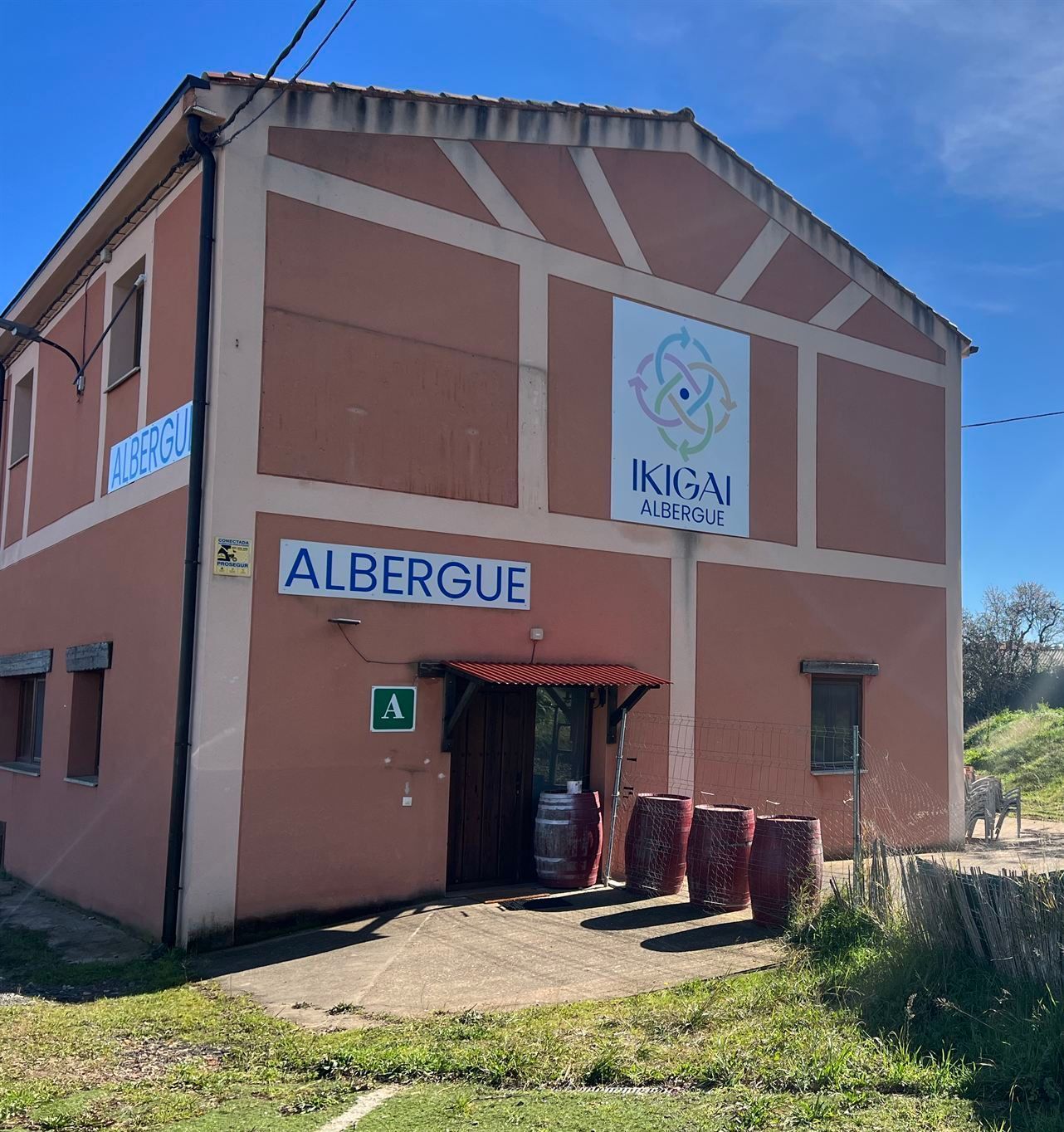 Un gran edificio naranja con barriles delante.