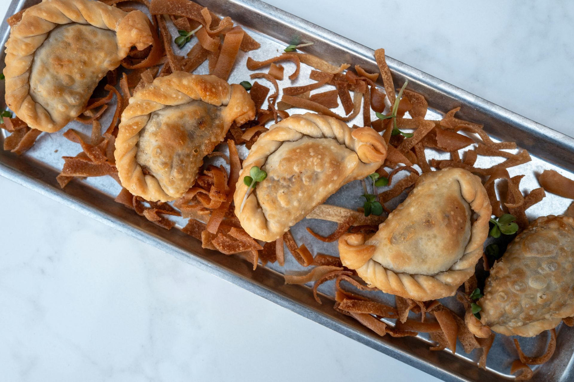 Una bandeja de comida con albóndigas fritas y fideos sobre una mesa.