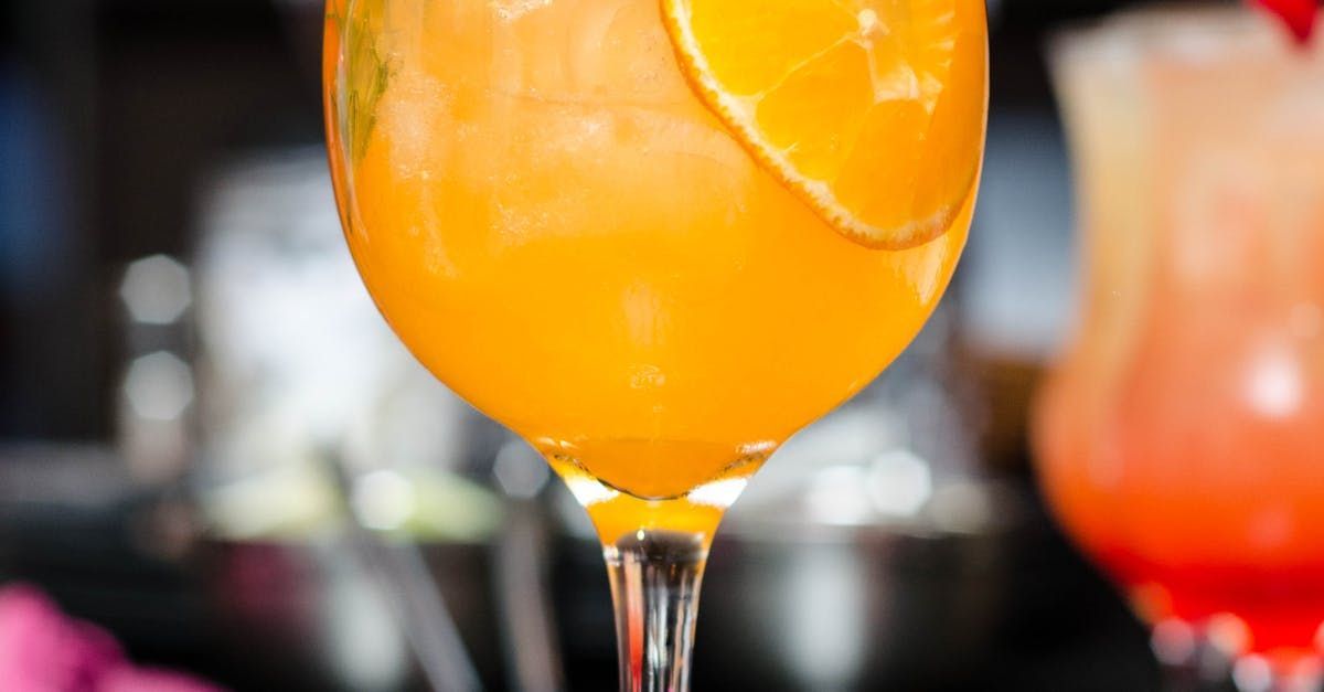 Un primer plano de un vaso de jugo de naranja con una rodaja de naranja dentro.