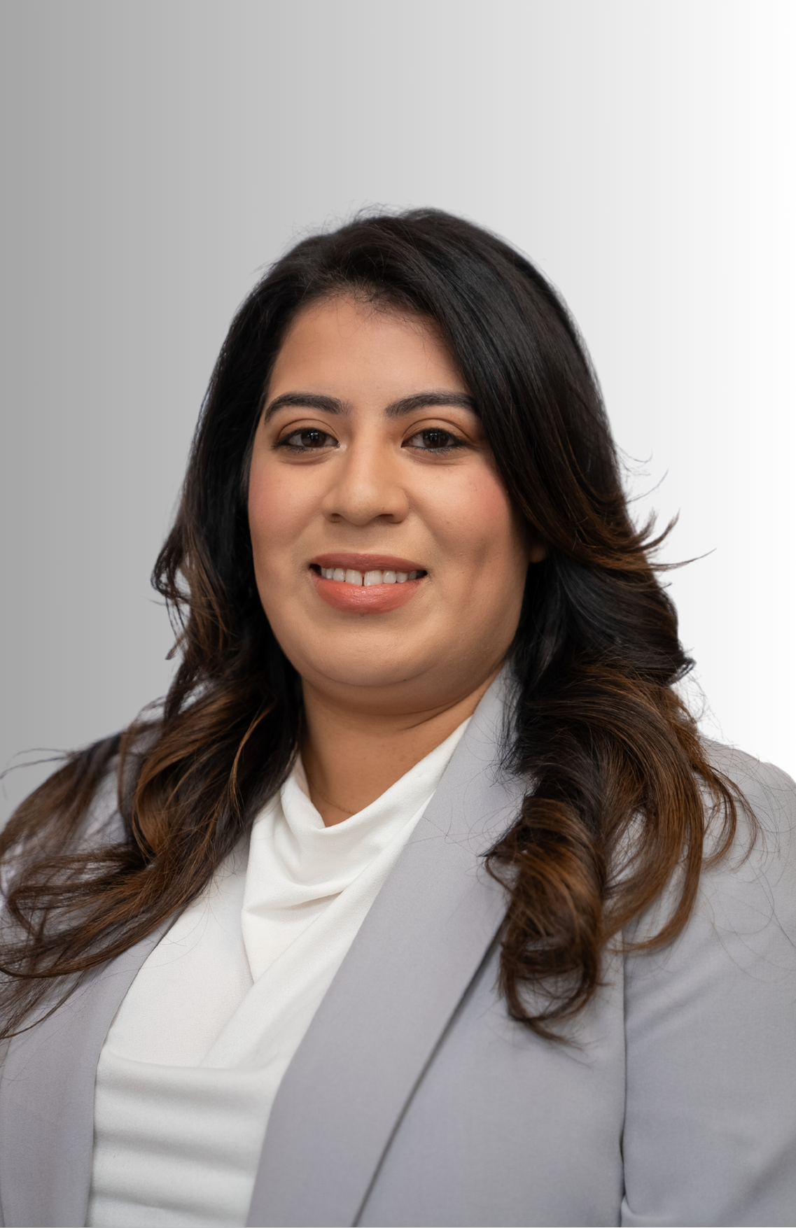 A woman in a gray jacket and white shirt is smiling for the camera.