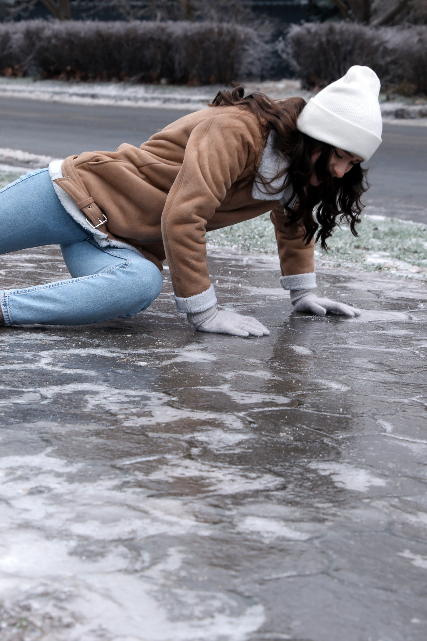 a woman is crawling on the ice on the side of the road .