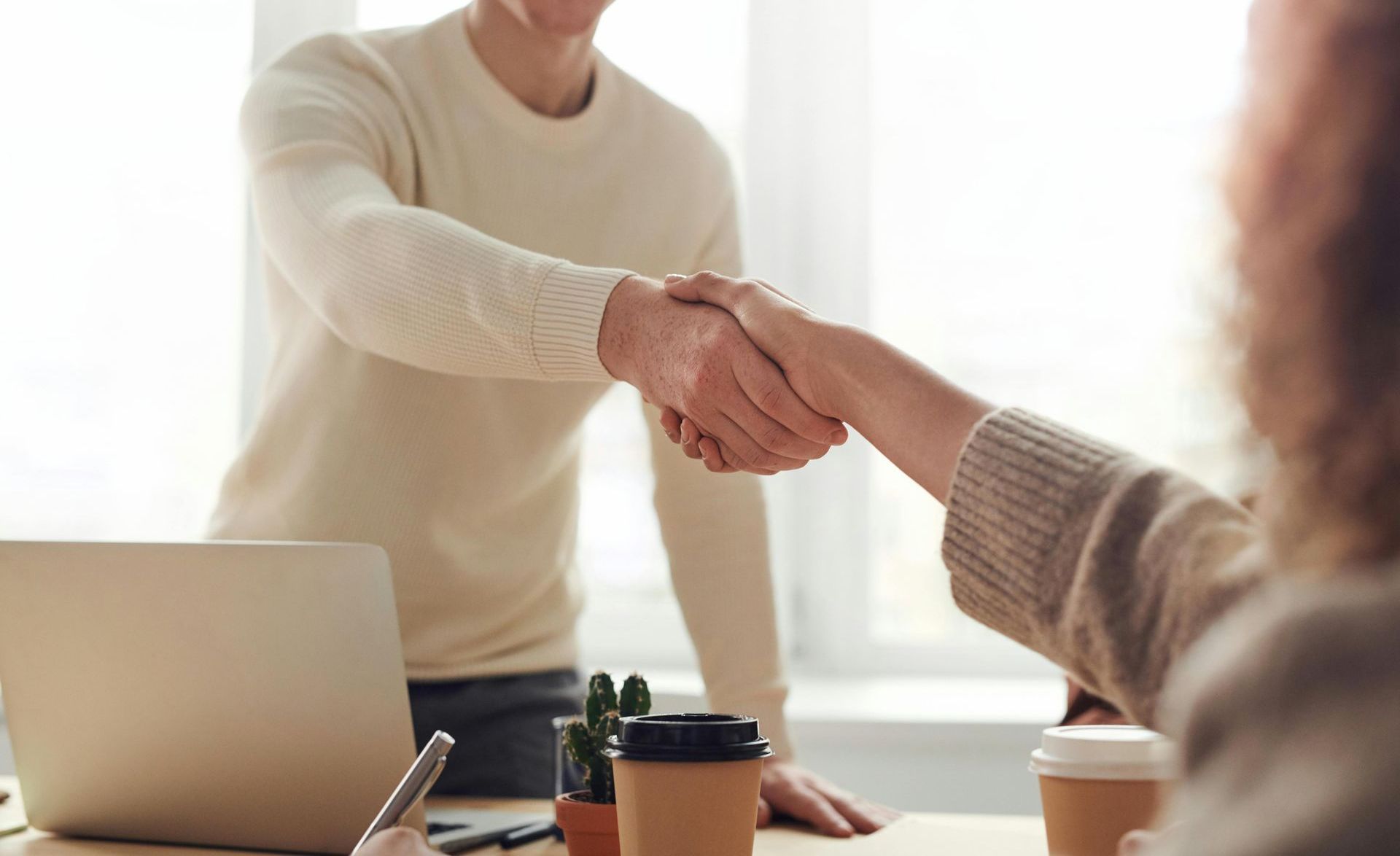 A man and a woman are shaking hands in an office.