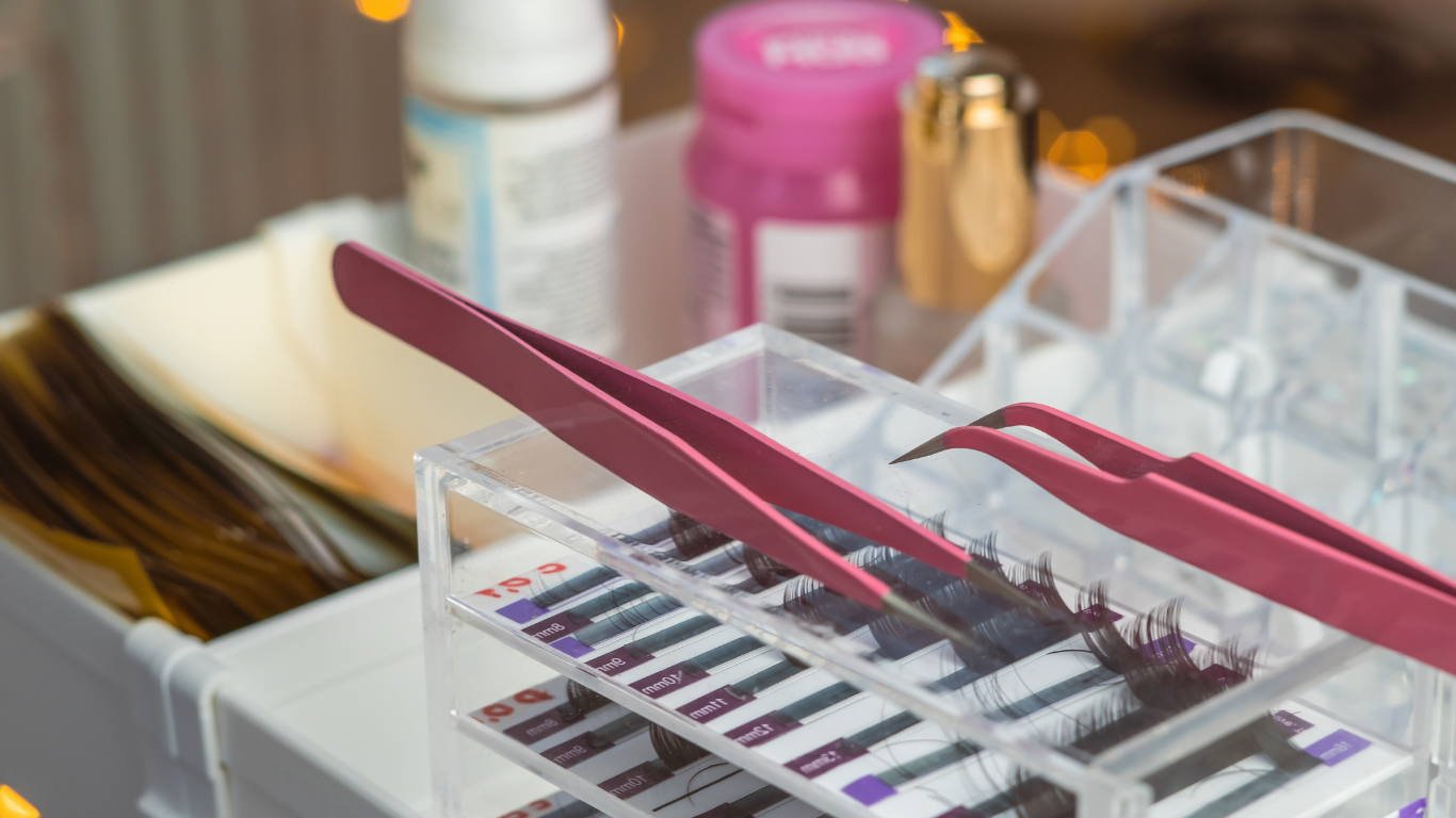 Woman with pale skin, dark hair pulled back, rosy lips, hand near chin, against peach background.