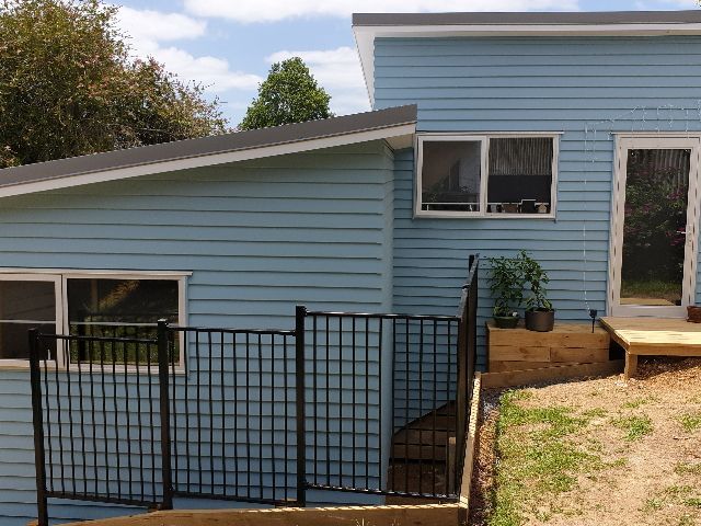 A blue house with a black fence in front of it.