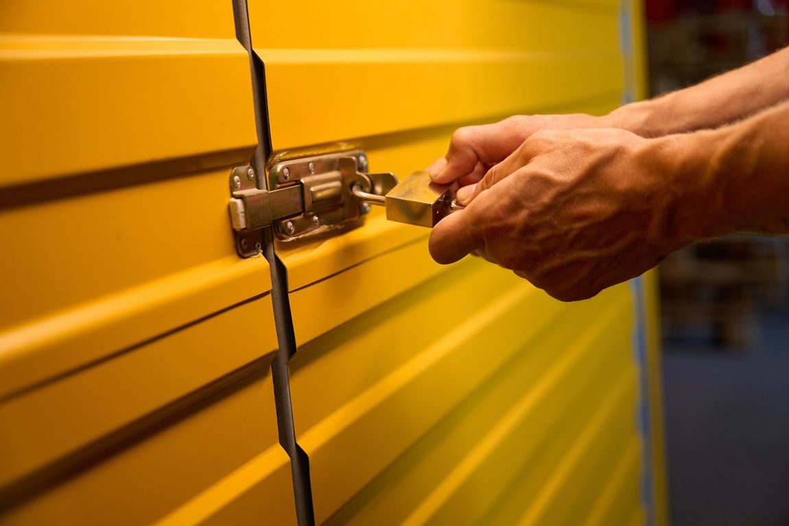 A person is opening a yellow door with a key.