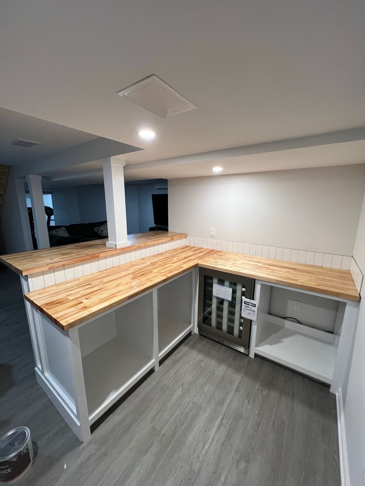 L-shaped kitchen island with white cabinets, butcher block countertops, a wine rack, and recessed lighting.