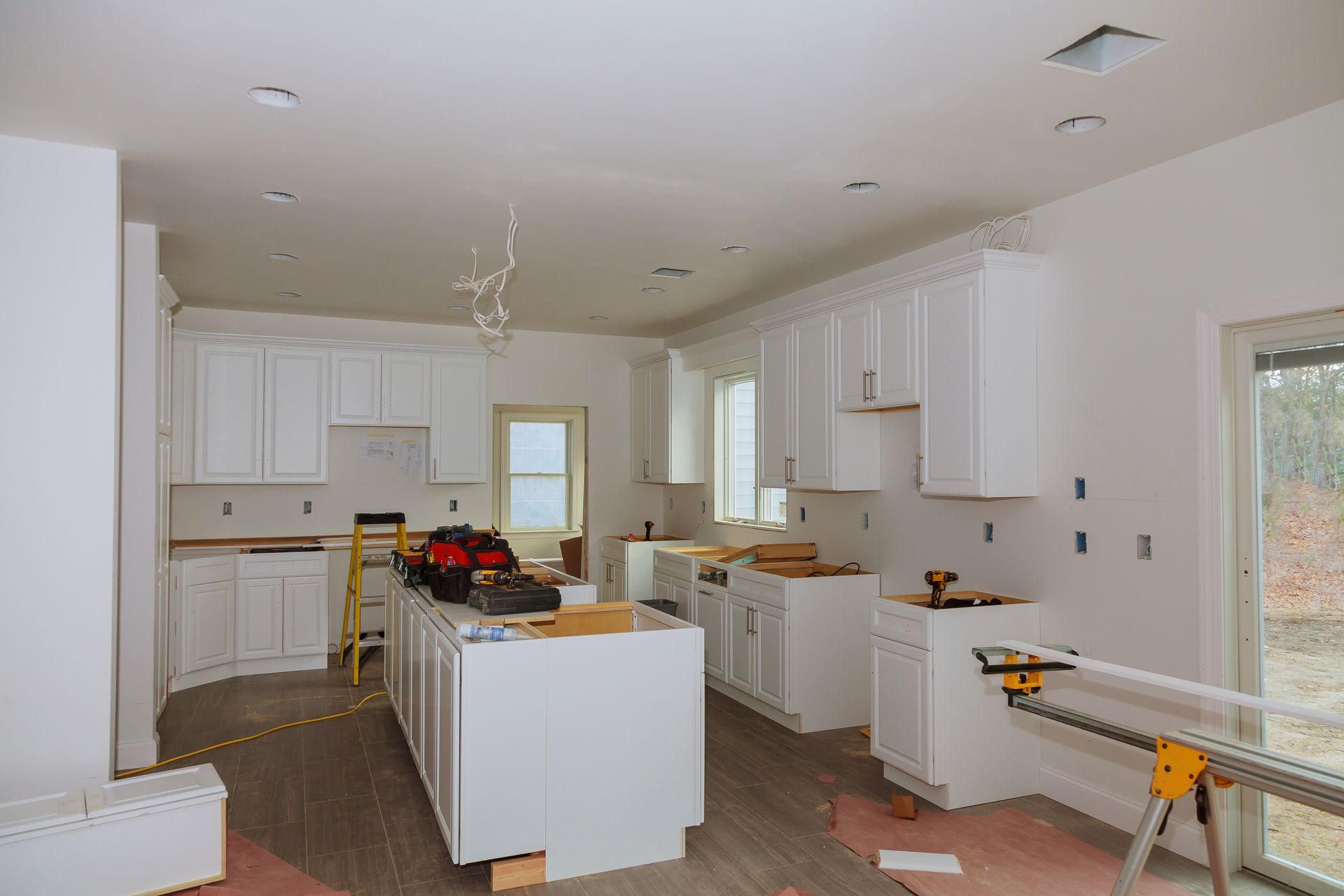 A kitchen under construction with white cabinets and a large island.