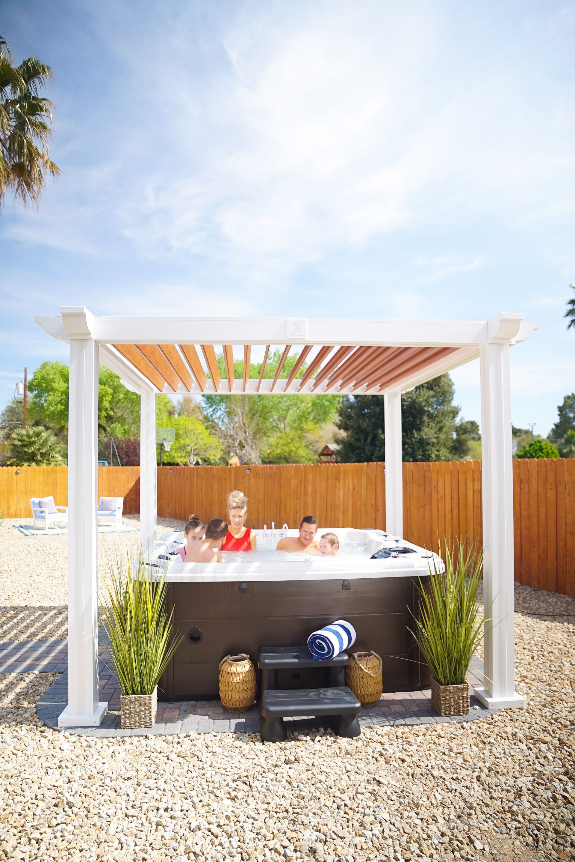 A group of people are sitting in a hot tub under a pergola.