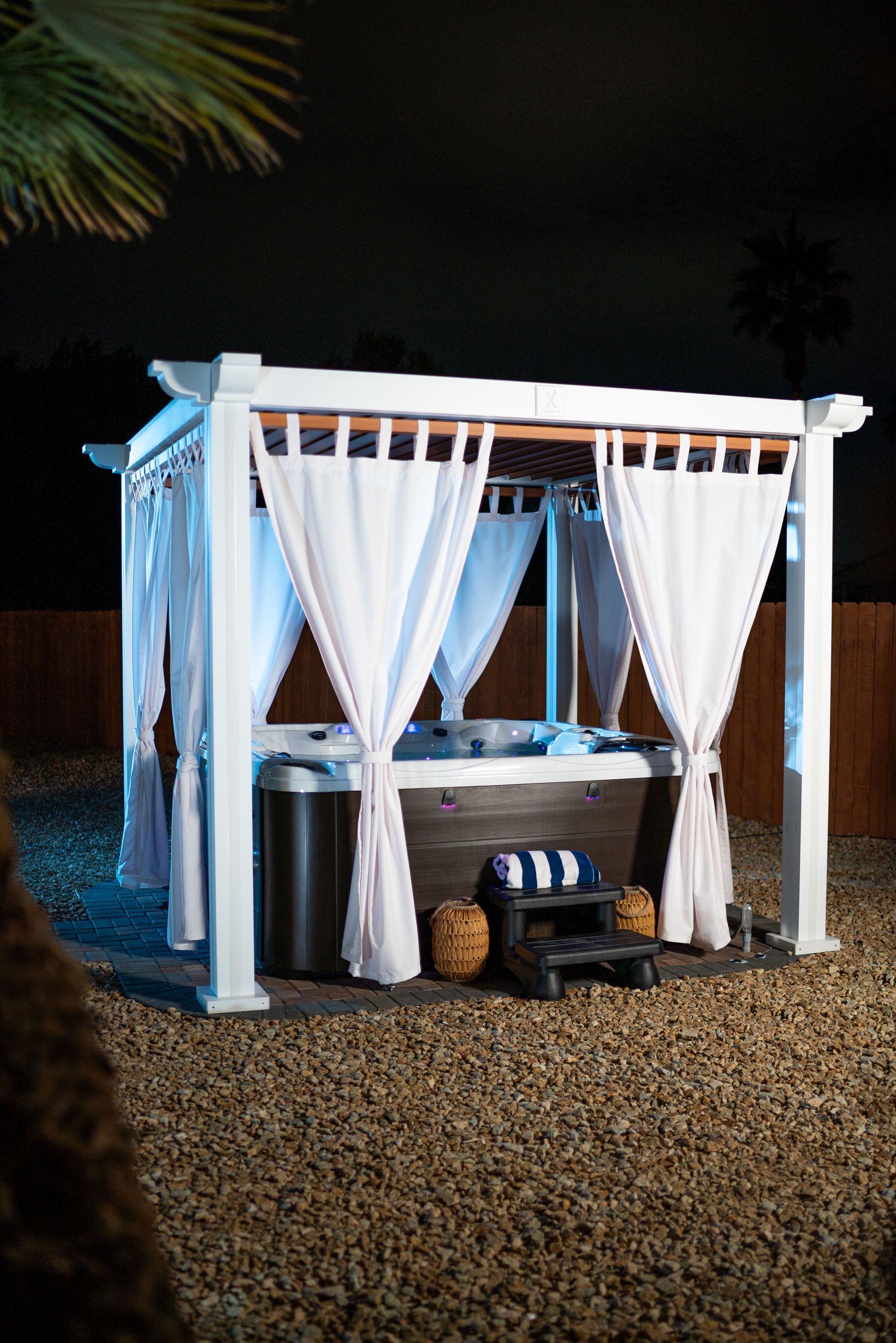 A hot tub is under a canopy with white curtains.