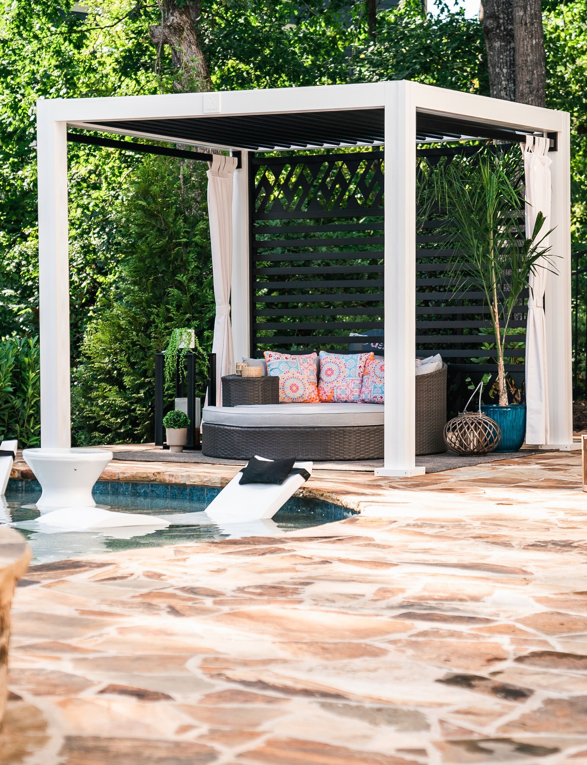 There is a pergola with a couch underneath it next to a pool.