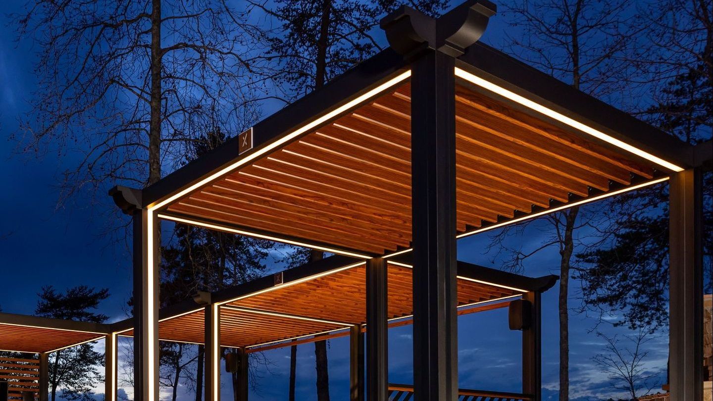 A pergola with lights on it is lit up at night.