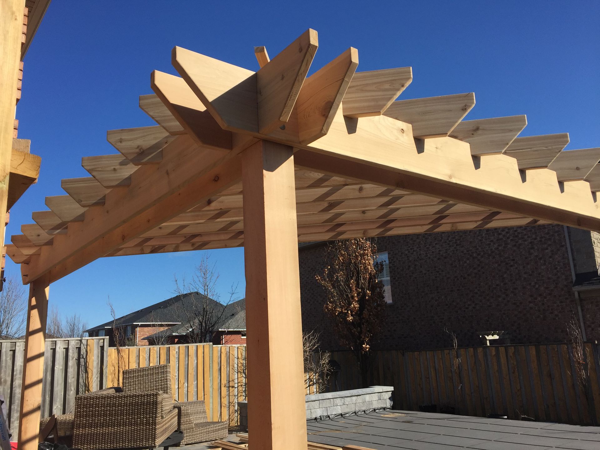 A wooden pergola is in the backyard of a house