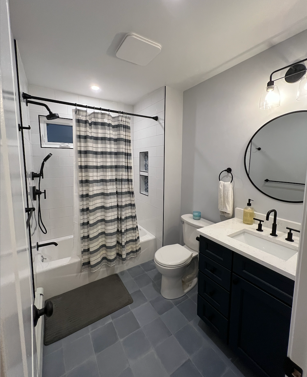 A bathroom with a toilet , sink , shower and mirror.