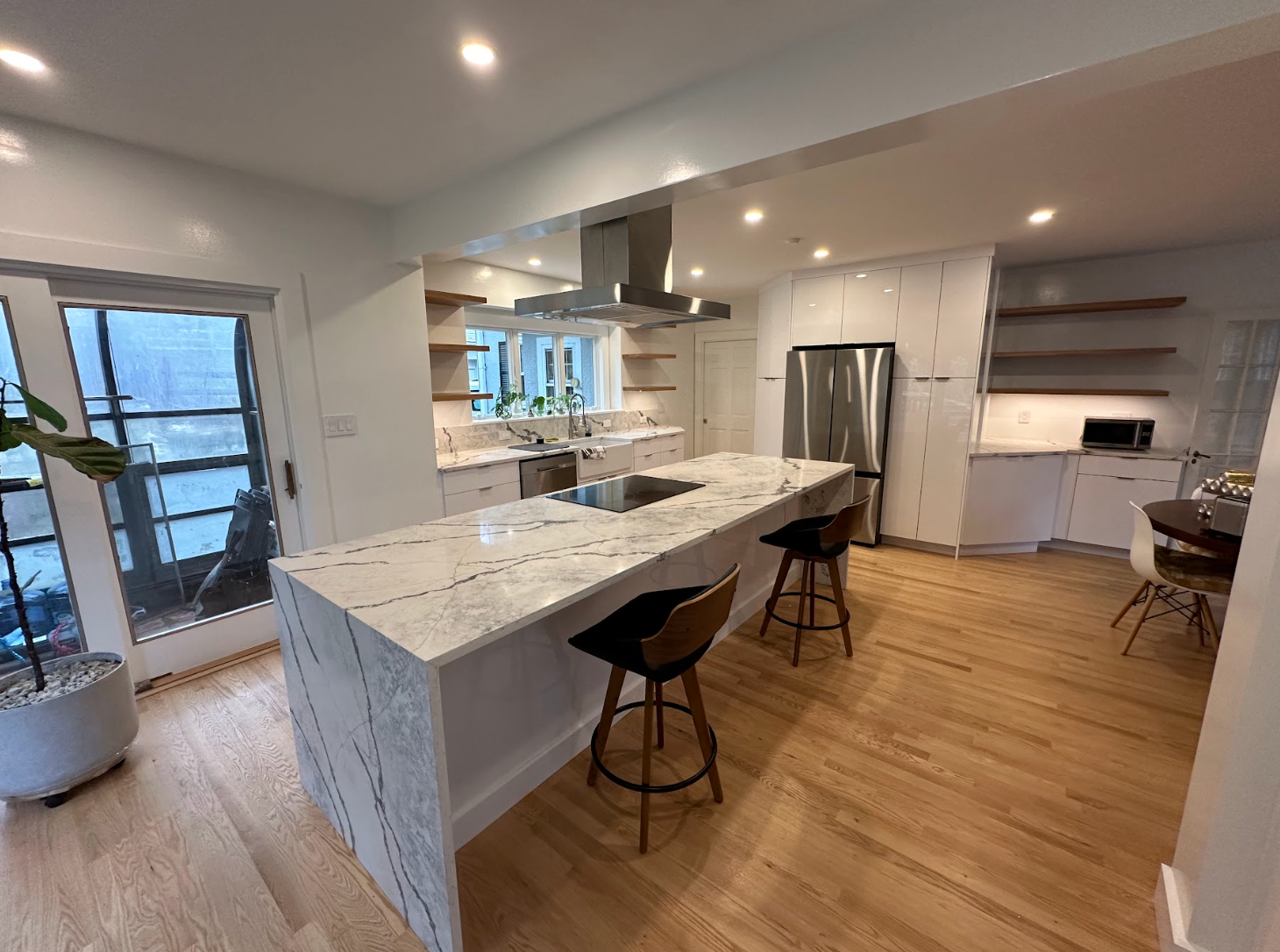 A kitchen with a large island , stools and a refrigerator.