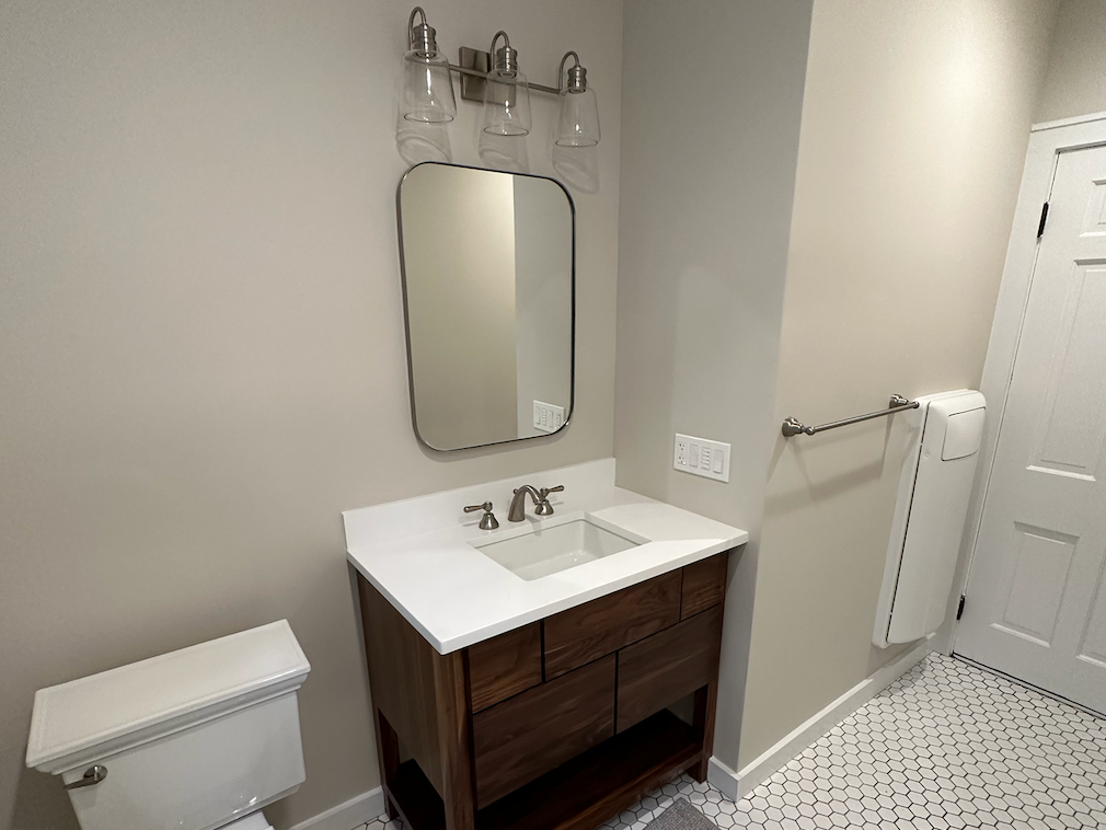 A bathroom with a sink , toilet and mirror.