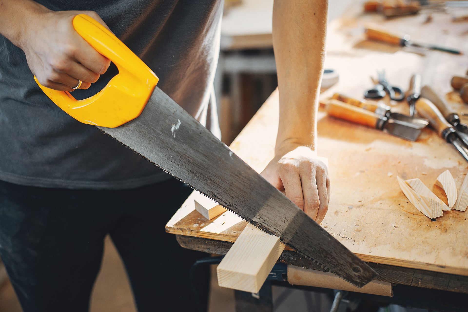 A man is cutting a piece of wood with a saw.