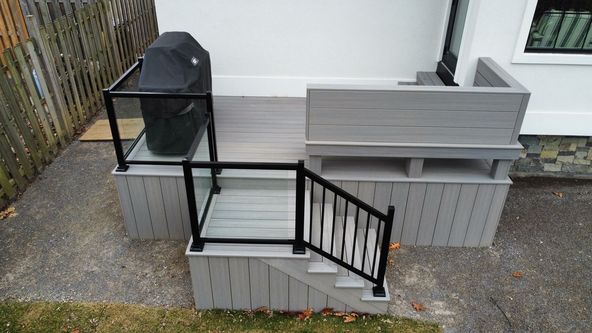 A deck with stairs leading up to it and a grill on it.