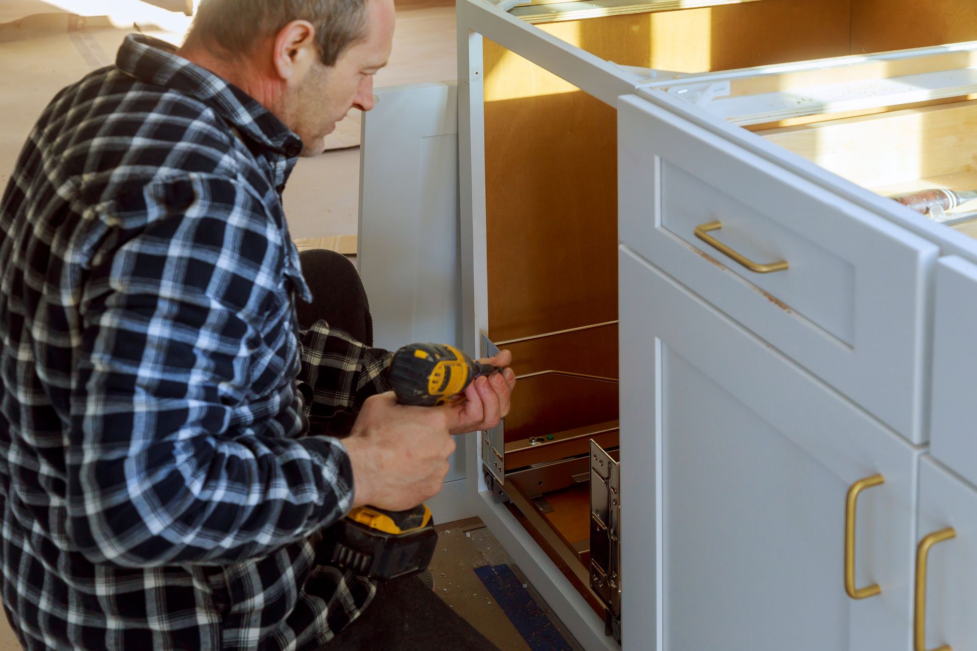 A man is drilling in a cabinet