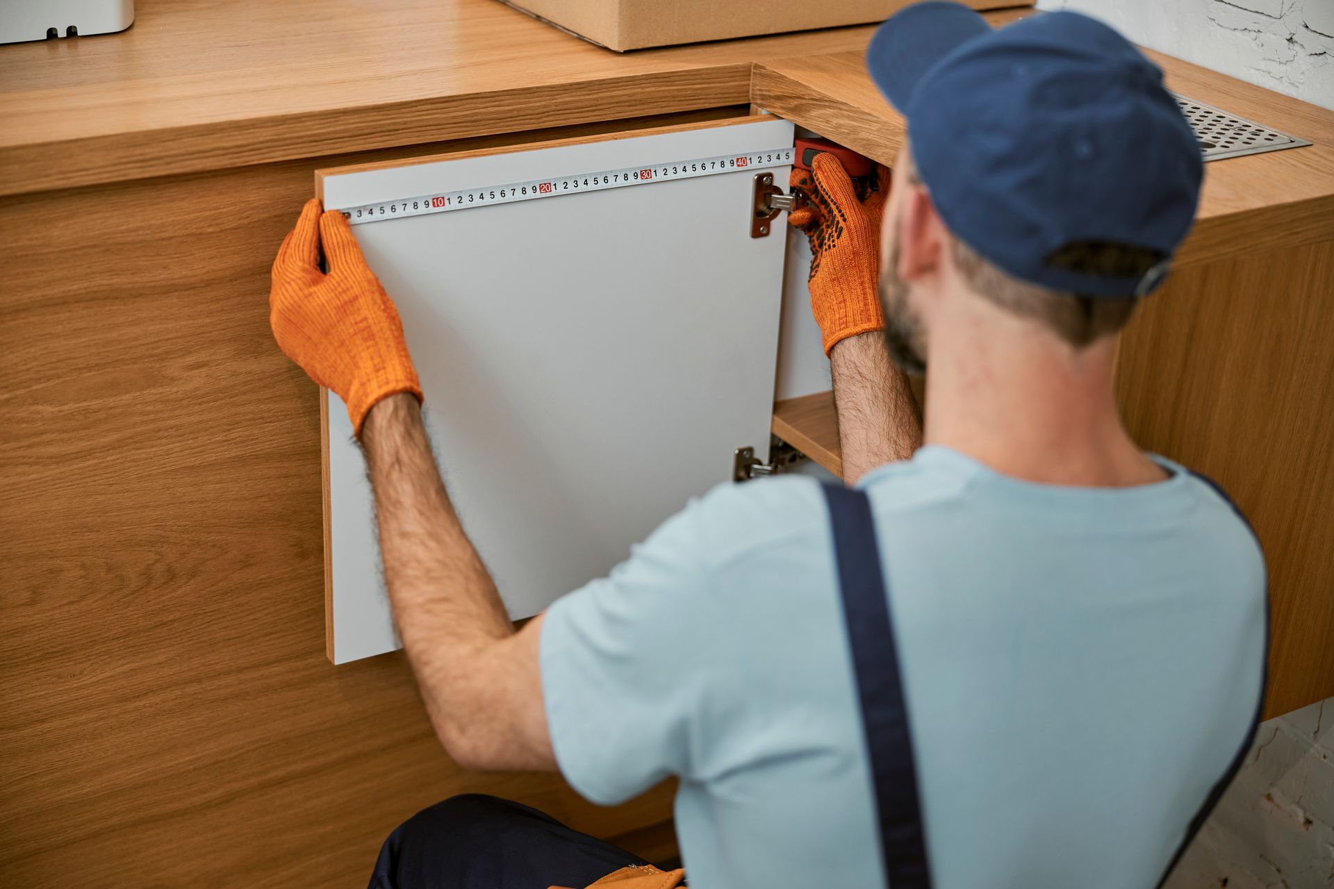 A man is installing a cabinet door in a kitchen.