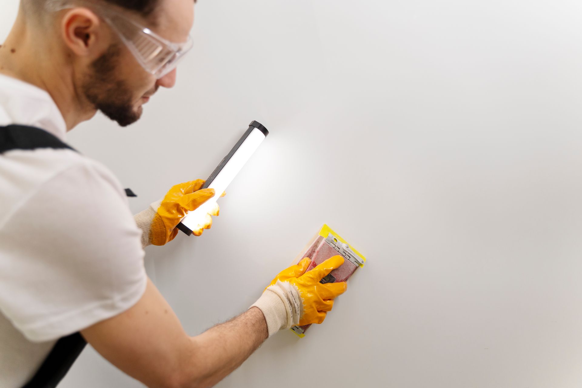 A man is cleaning a wall with a sponge and a light.