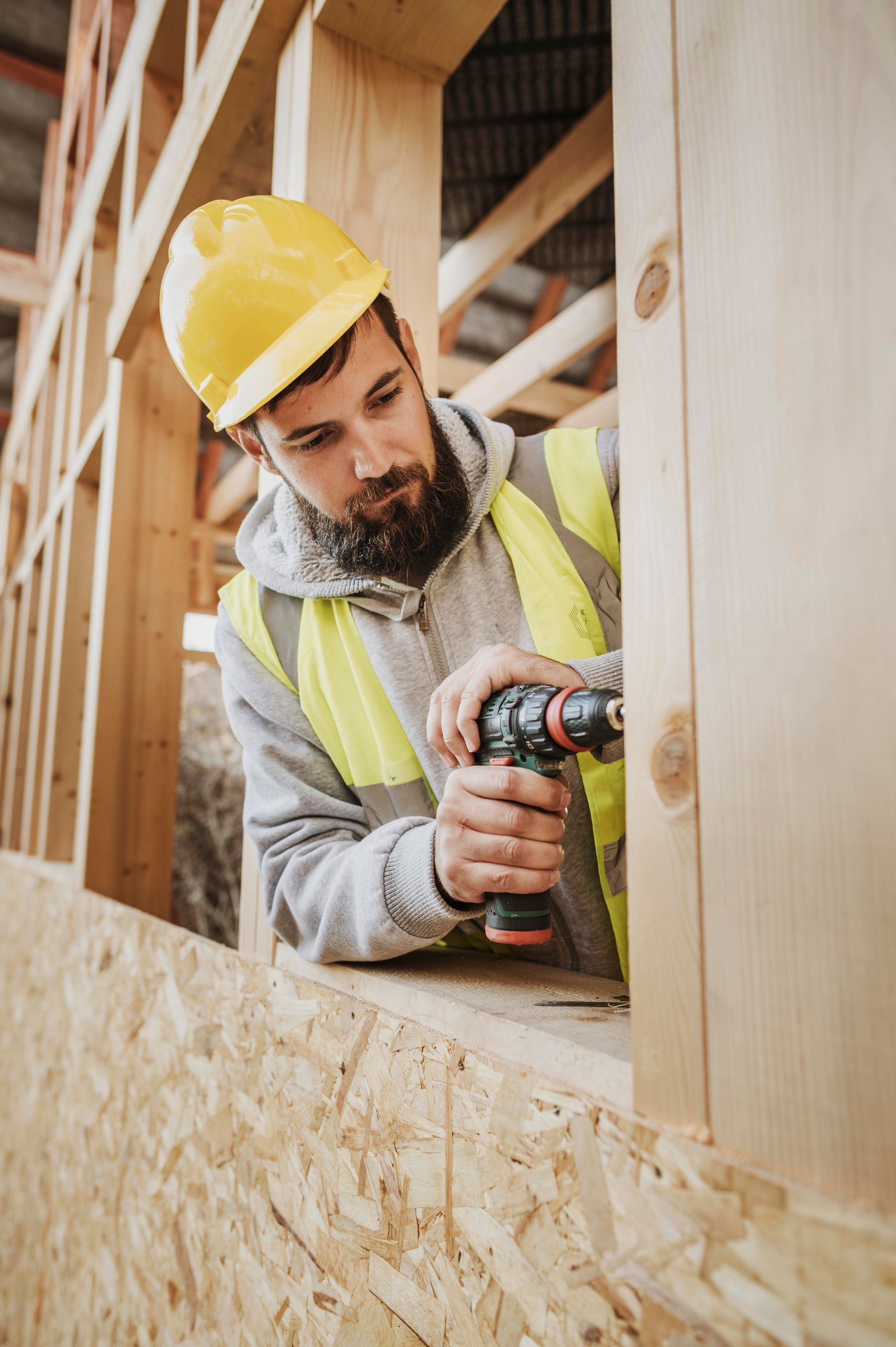 A man is using a drill on a wooden wall.