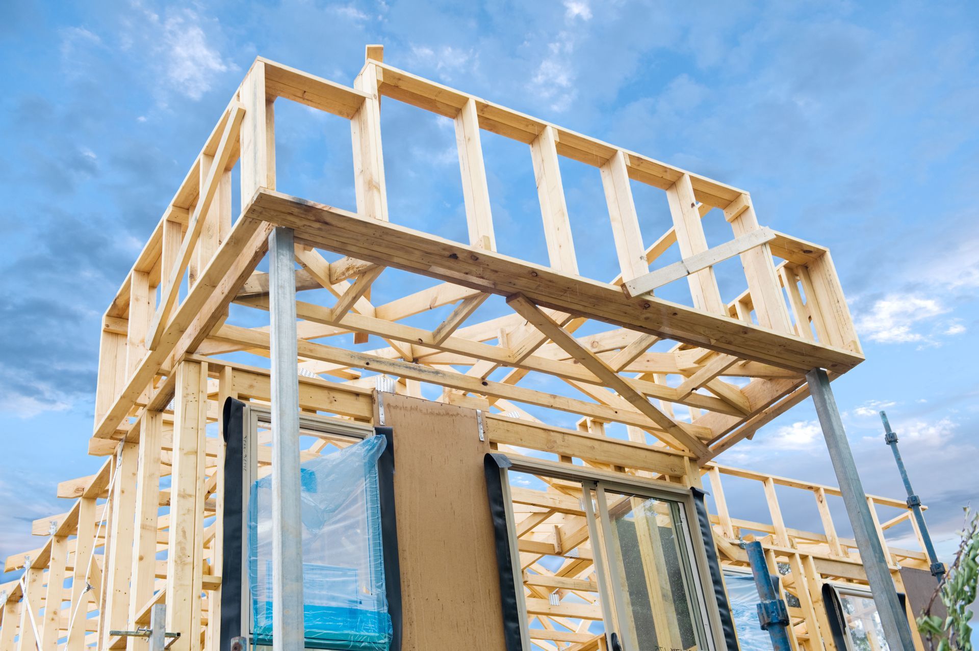 A wooden house is being built with a blue sky in the background.