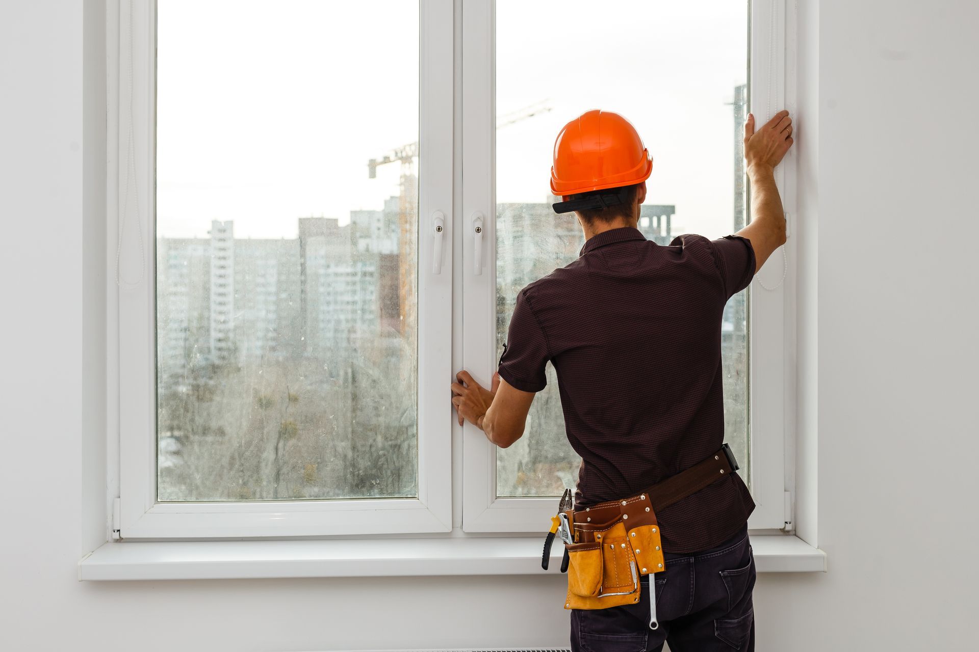 A man wearing a hard hat is installing a window.
