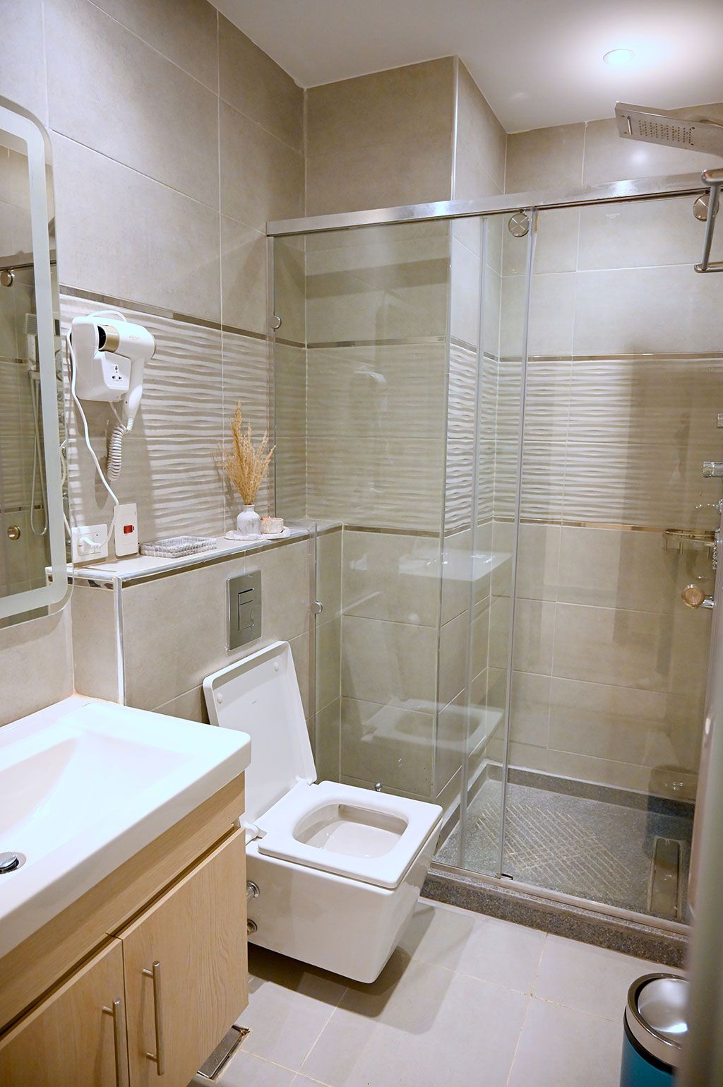 Modern bathroom with a glass shower, toilet, and vanity with a mirror.