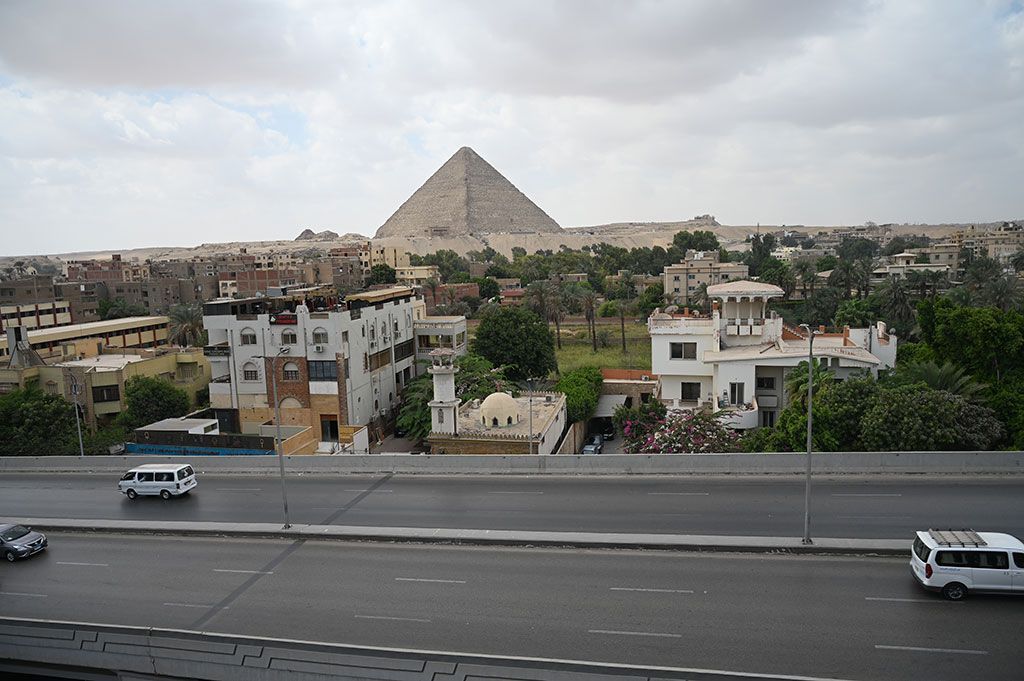 Great Pyramid of Giza rising above buildings and a road in Egypt.