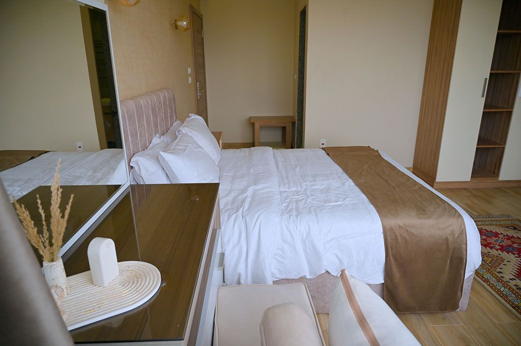 Bedroom with a bed, nightstand, and rug. Earth tones dominate.