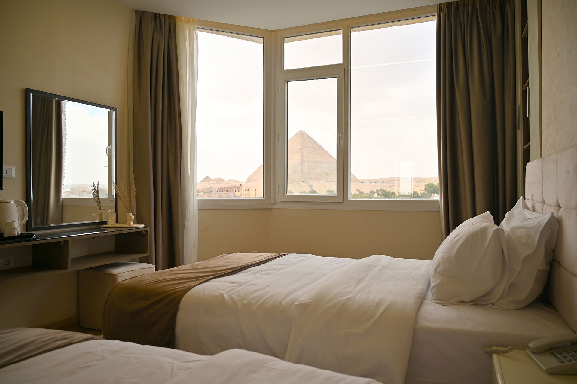 Hotel room with twin beds and a window view of pyramids.