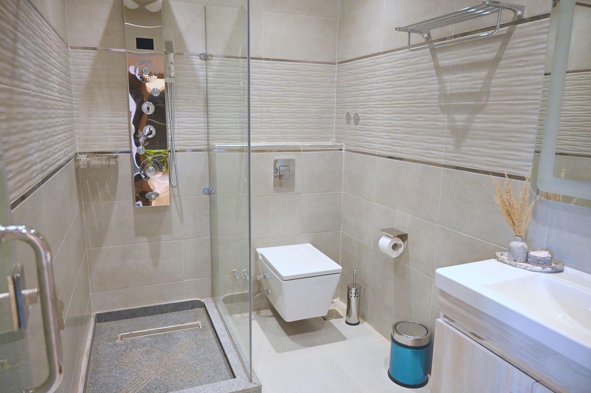 Modern bathroom with shower stall, toilet, sink, and textured light-colored walls.