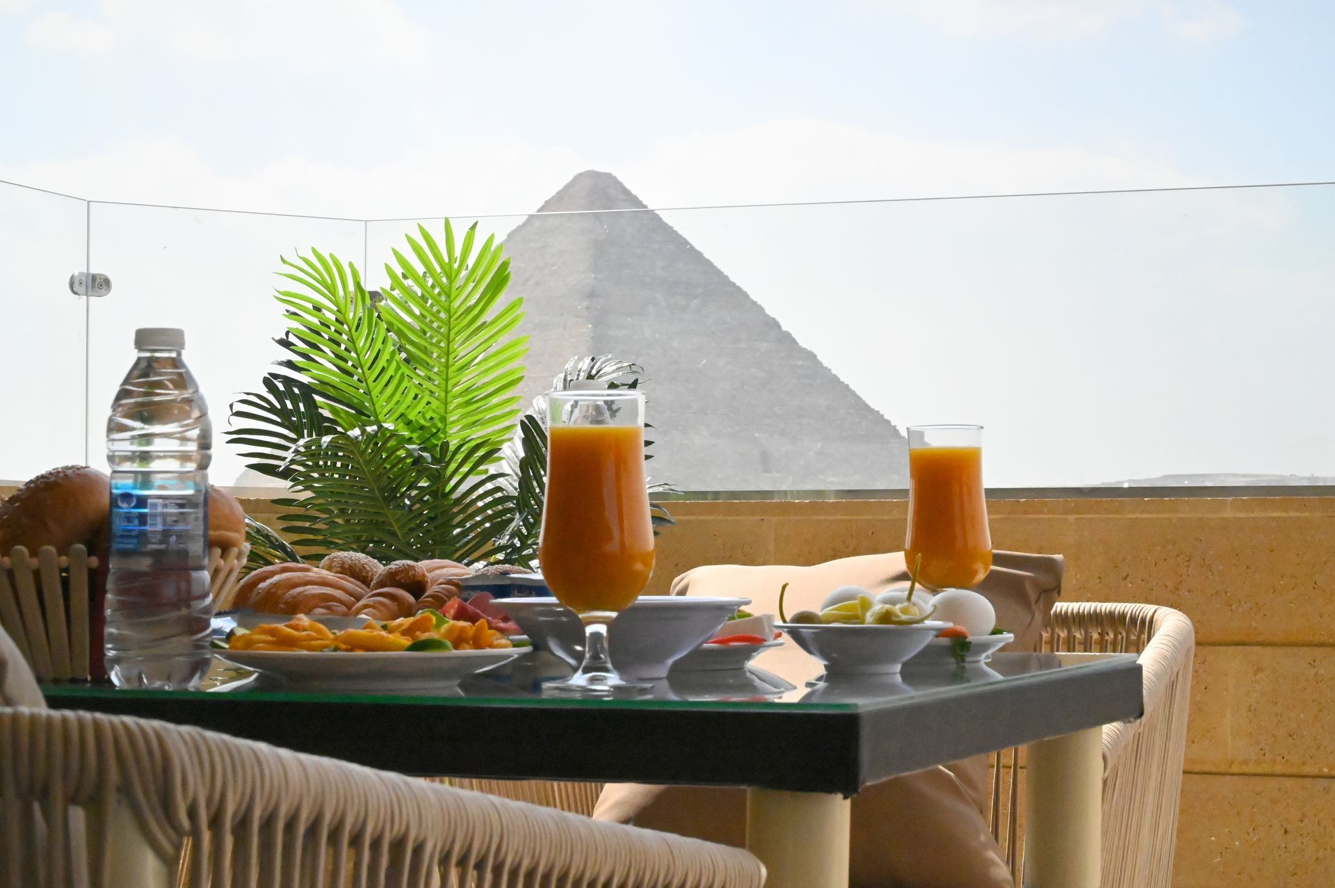Breakfast table with pyramid view. Orange juice, bread, and eggs on the table, a pyramid in the background.