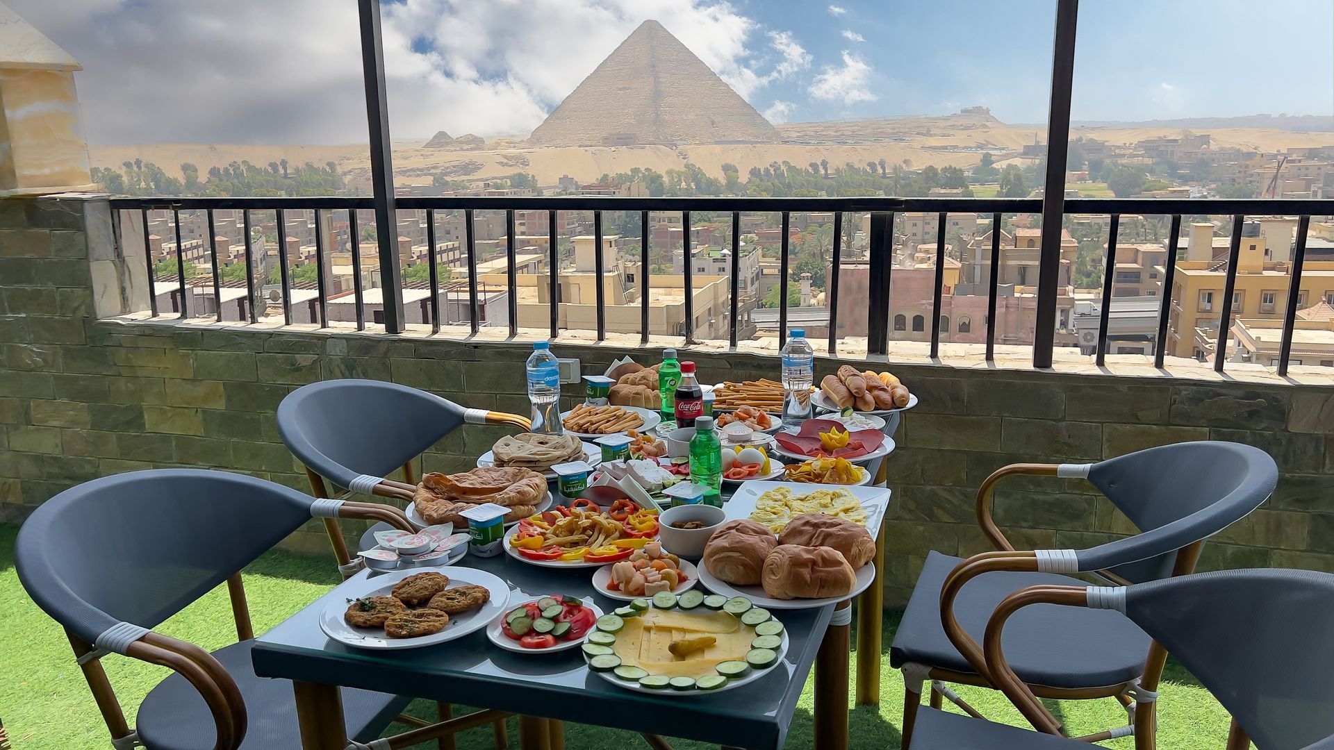 Outdoor dining table laden with food, Great Pyramid in background.