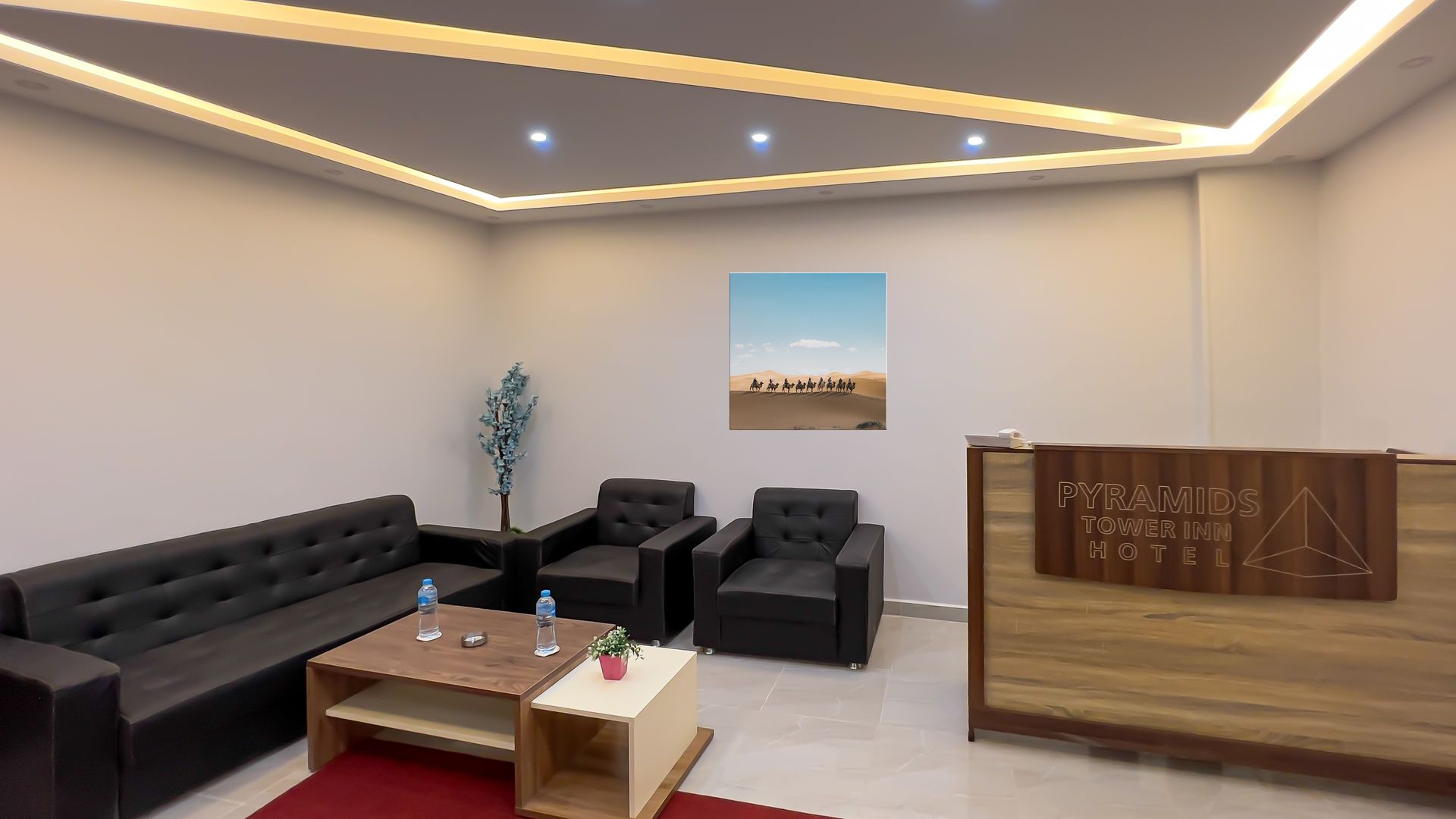Waiting area with black furniture, art, wooden reception desk, and decorative ceiling lights.