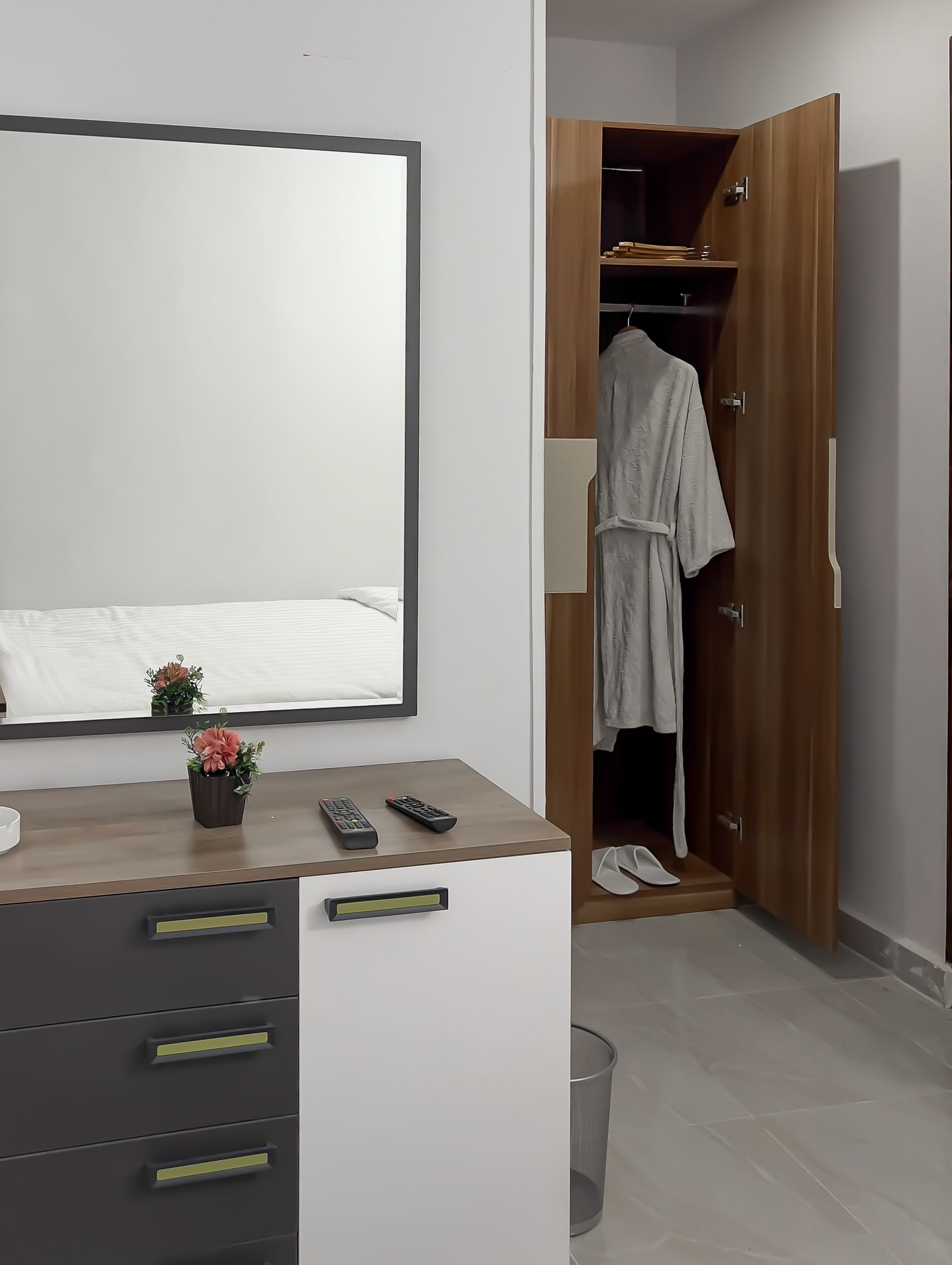 Bedroom with dresser, mirror, closet, and bed. A robe hangs in the open closet.