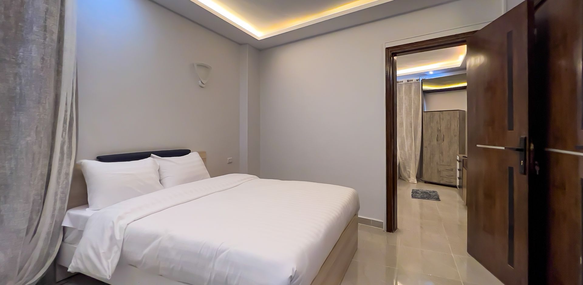 Bedroom with a bed, ajar door to a hallway, and neutral-colored walls.