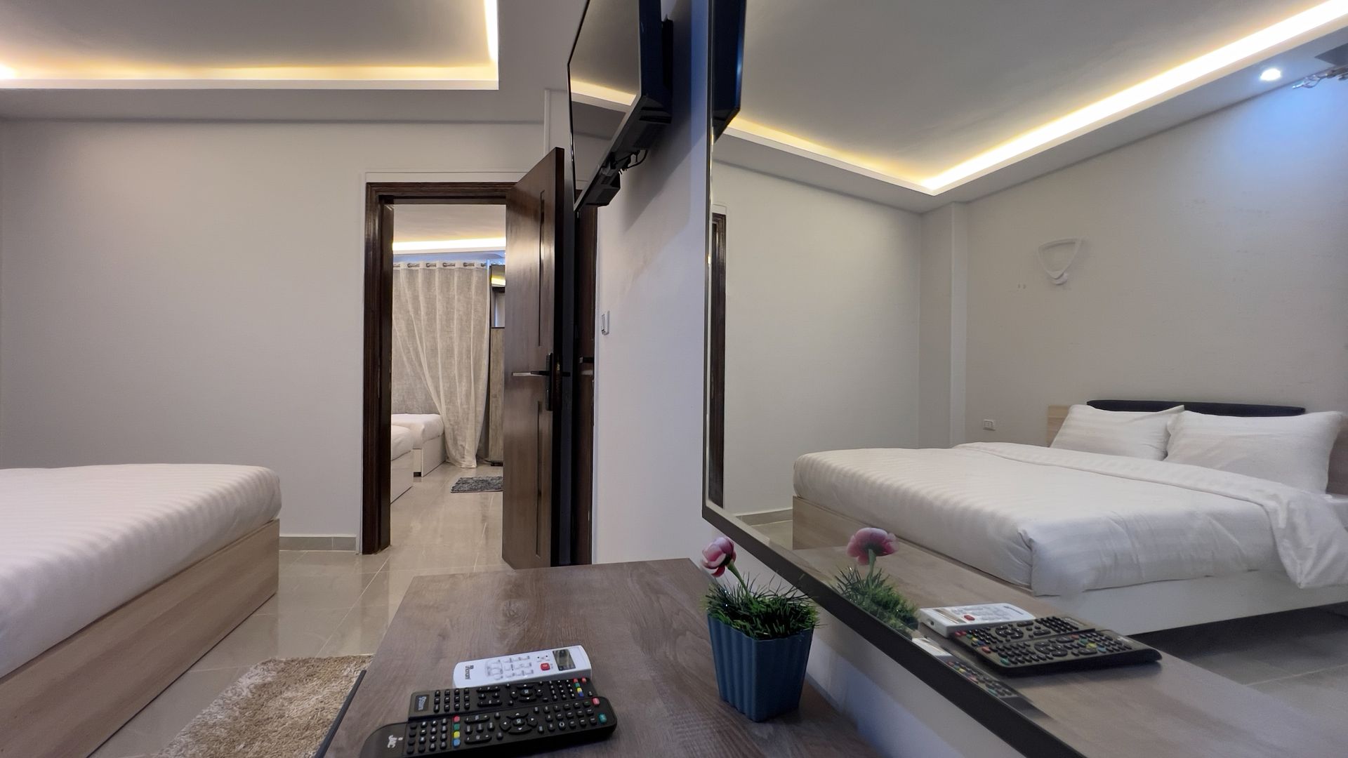 Bedroom interior with two beds, a TV, and an open doorway to another room.