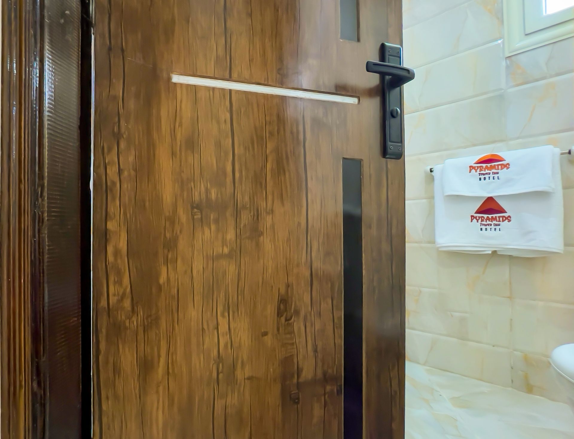 Wooden door with black handle, a partially visible towel rack with a folded towel.