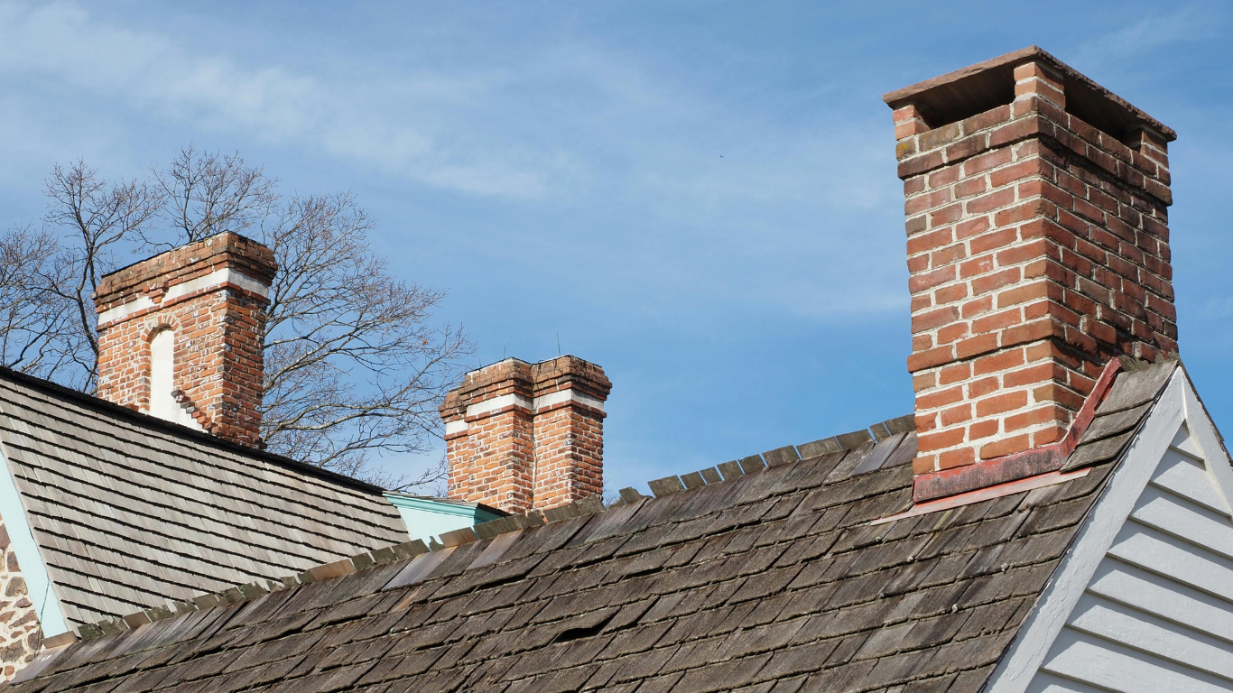 A brick chimney is sitting on top of a wooden roof.