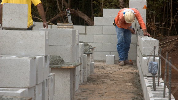Two construction workers are working on a brick wall.