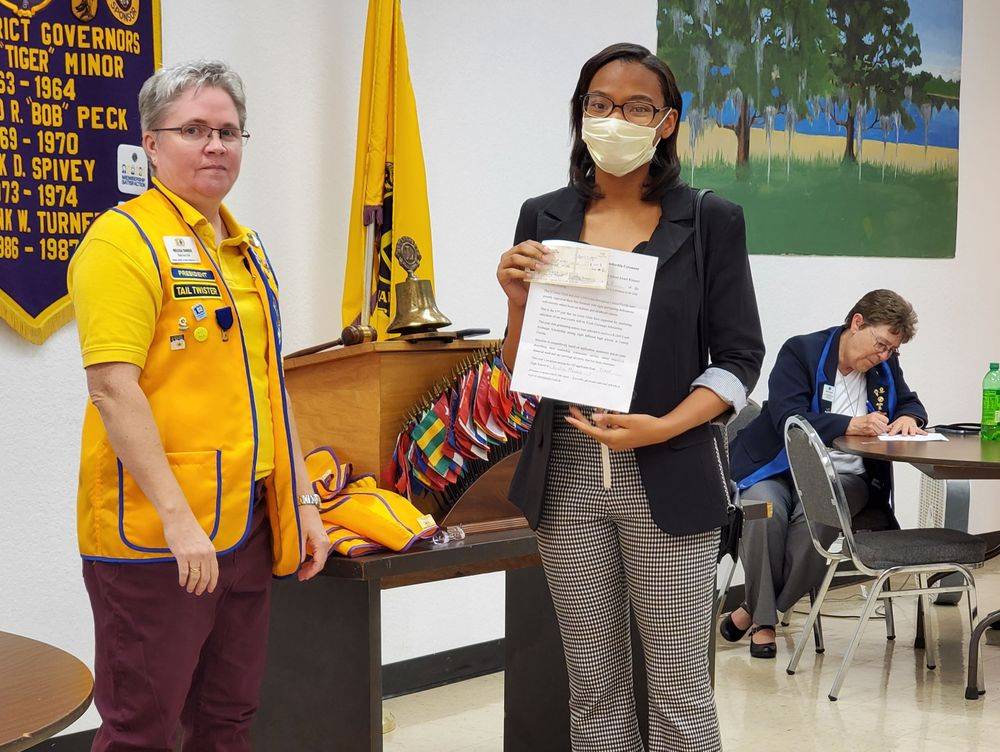 A woman wearing a mask is holding a piece of paper next to a woman in a yellow jacket.