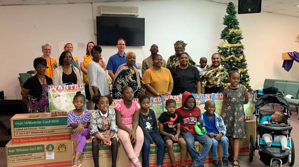 A group of people are posing for a picture in front of a christmas tree.