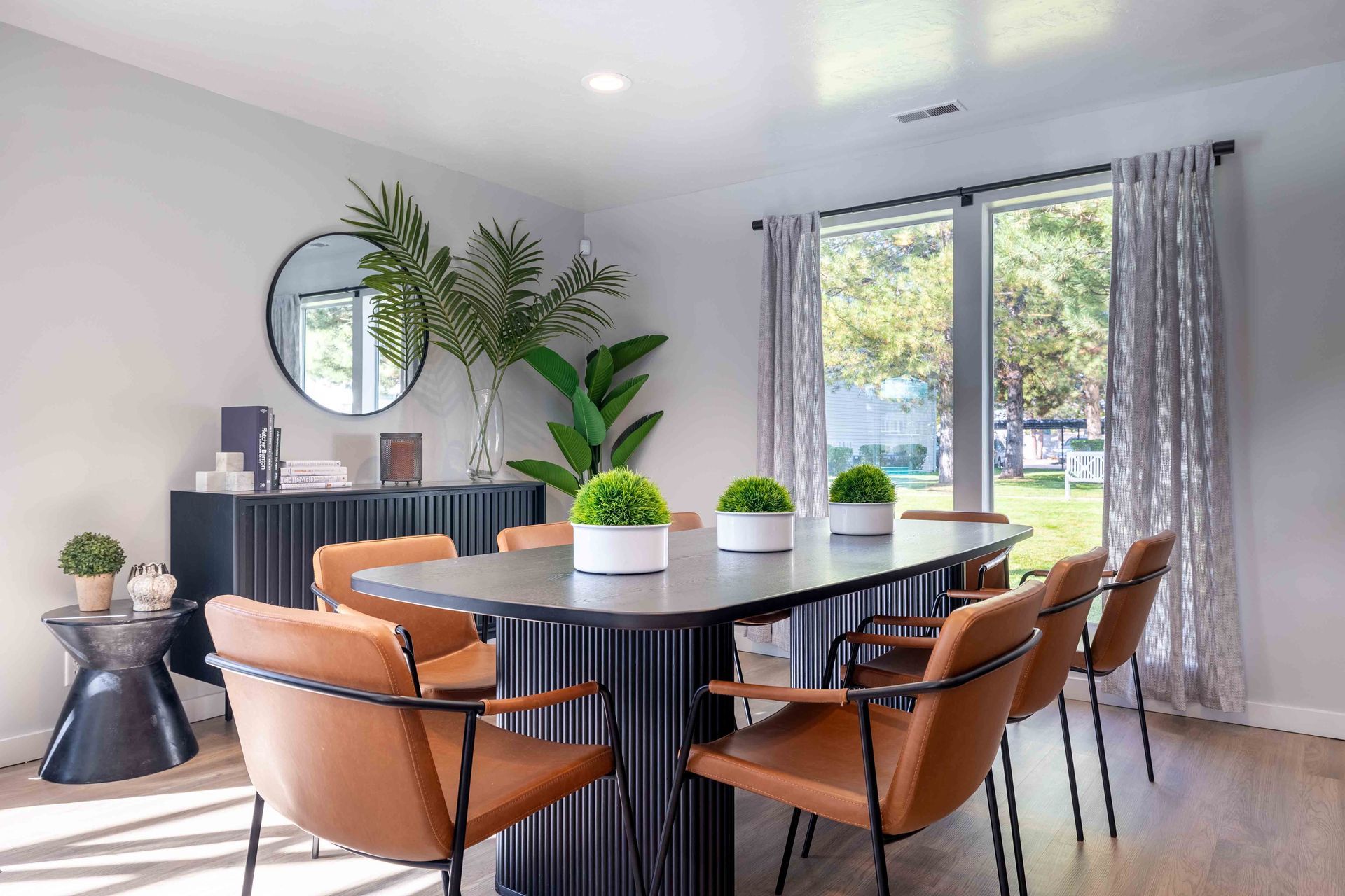 Modern dining room with a long table, brown chairs, and large window with view.