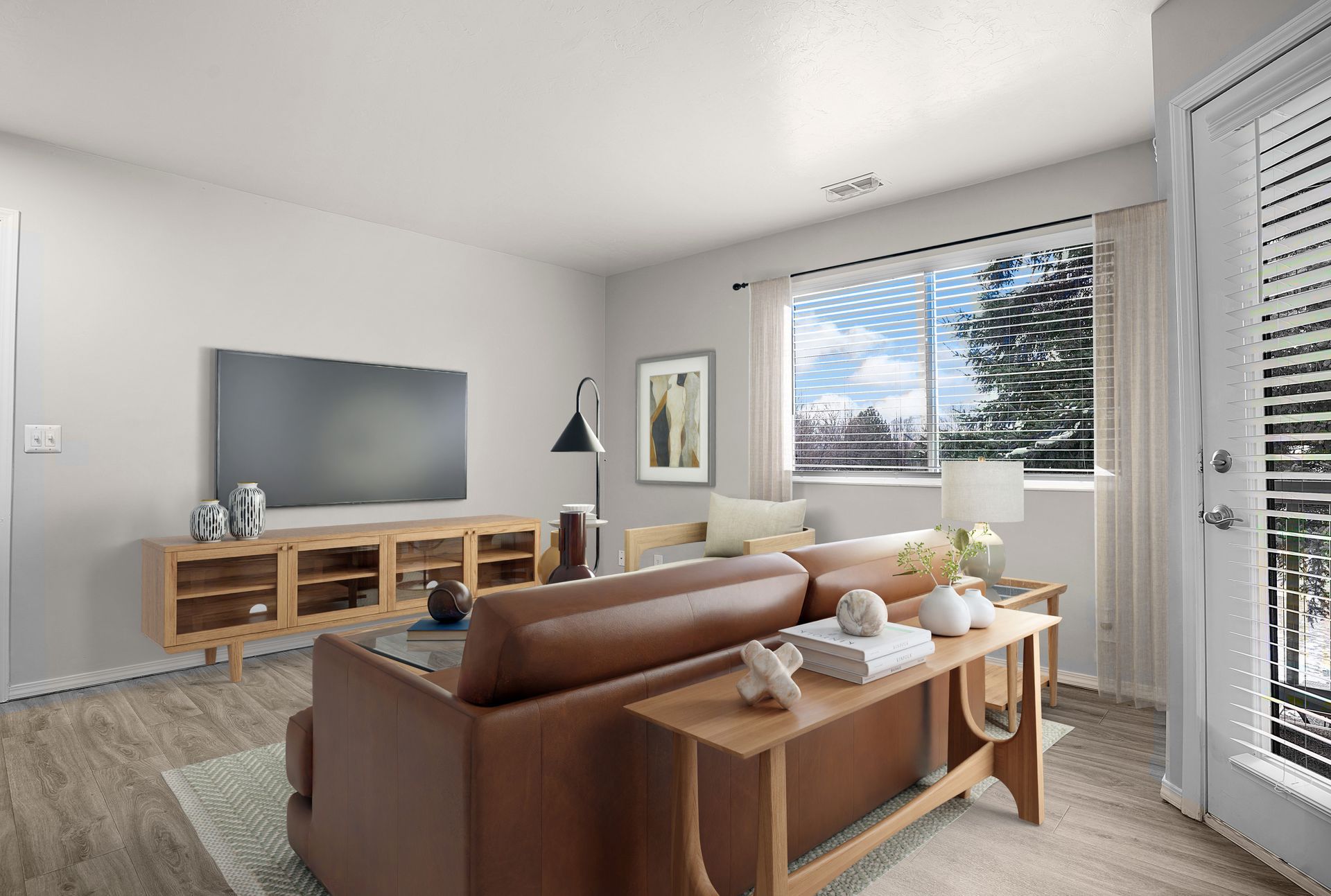 Living room with brown leather sofa, TV, and large window with balcony access.