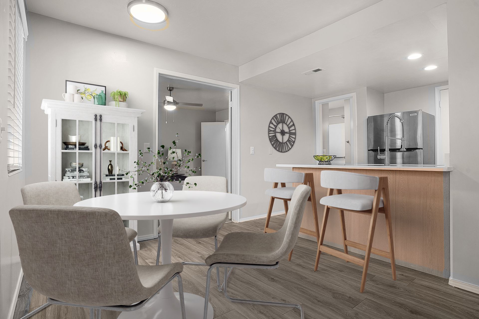 Dining area with white table, chairs, cabinets, and a bar with stools.
