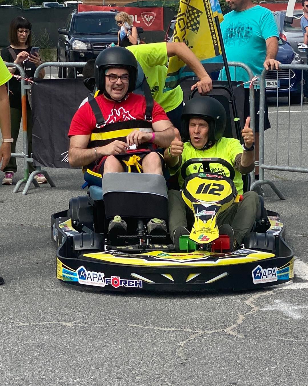 Due persone con il casco guidano un go-kart giallo con il numero 