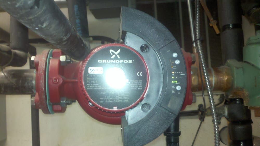 Red Grundfos pump on pipes with a black control panel.
