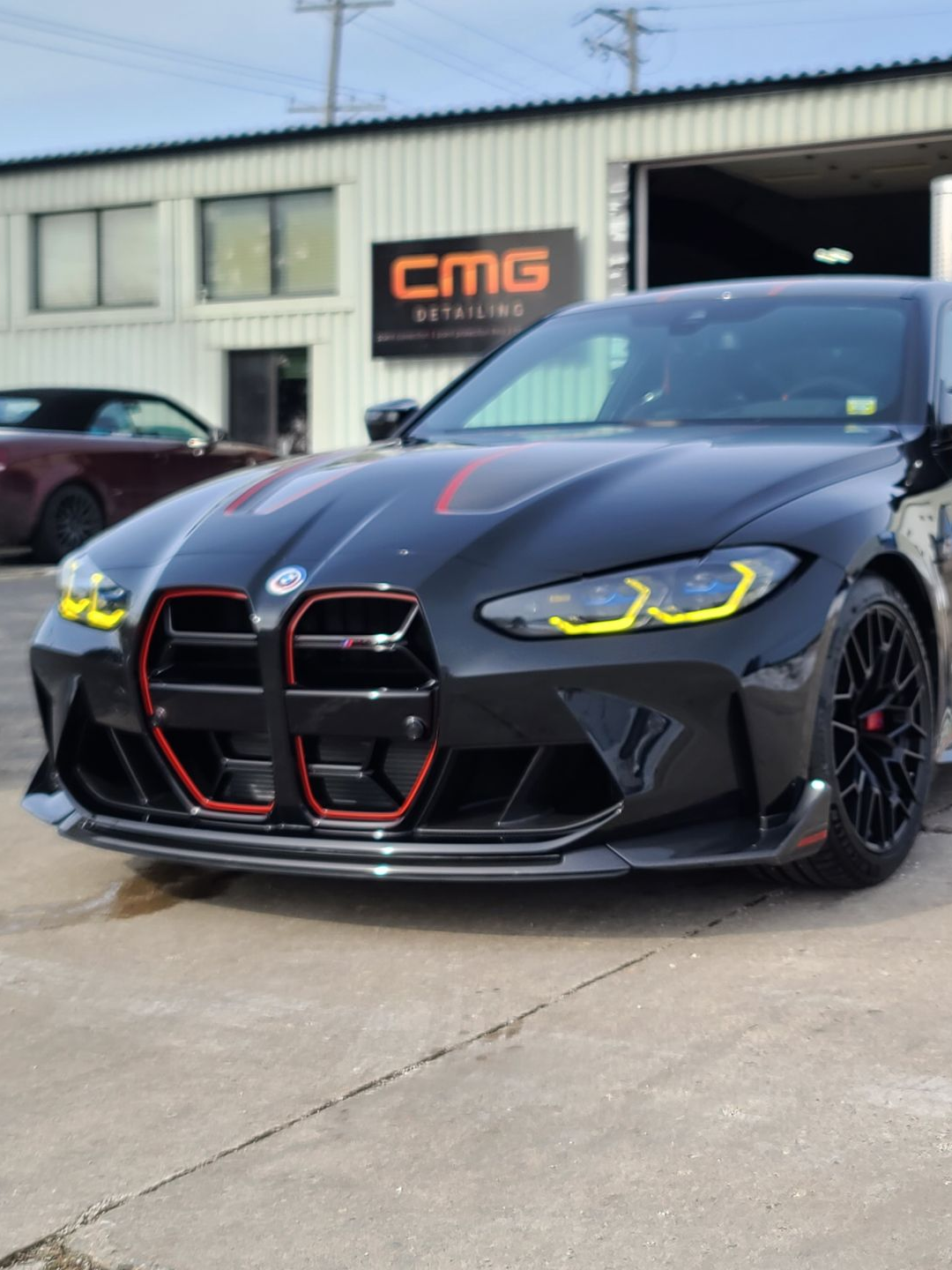 Person wearing black gloves cleaning a car tire with a yellow sponge.