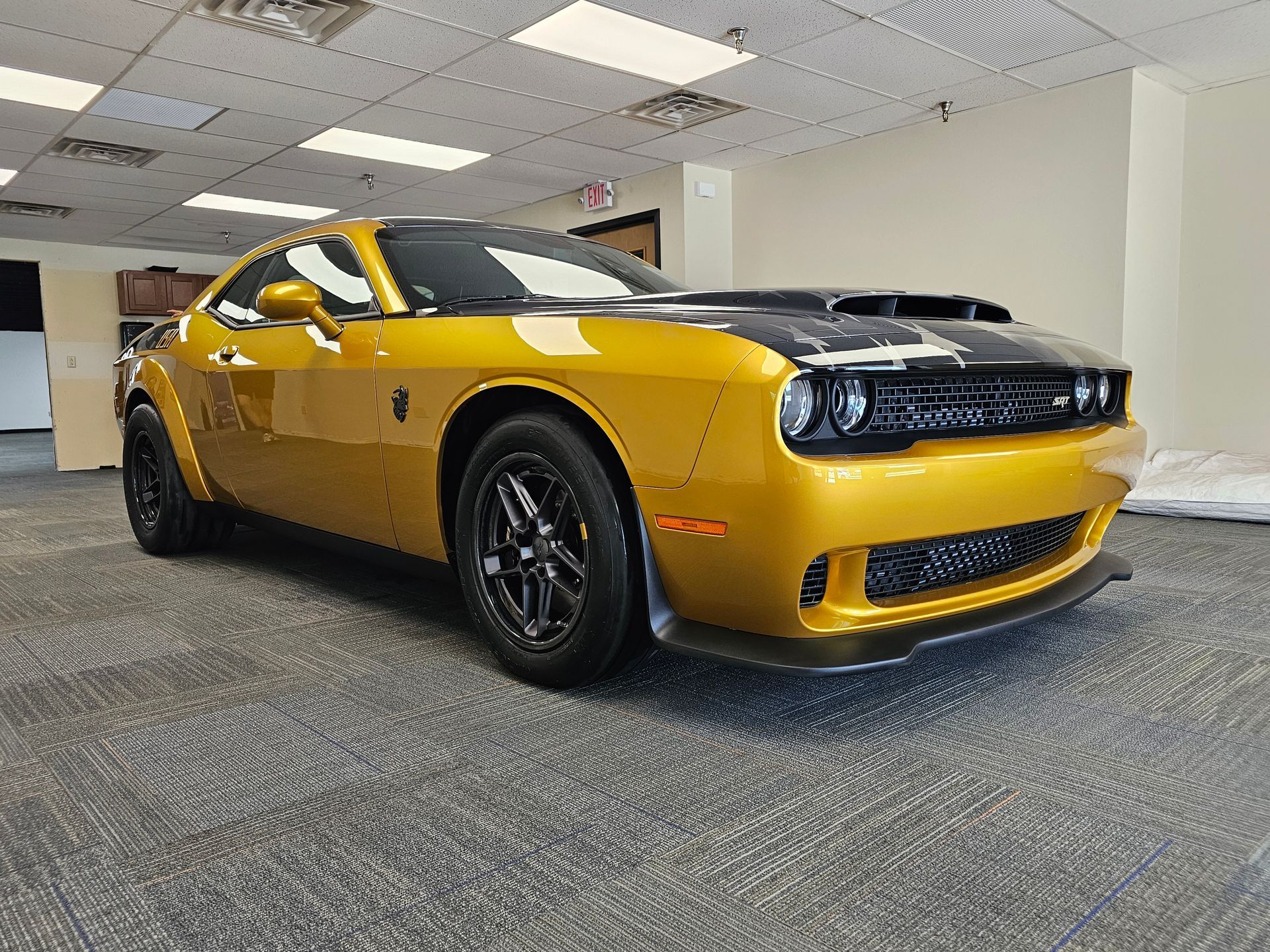 White Porsche Cayman GTS parked outside a building, black accents, bronze wheels.